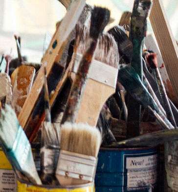 Table filled with Painbrushes and other Painting Supplies