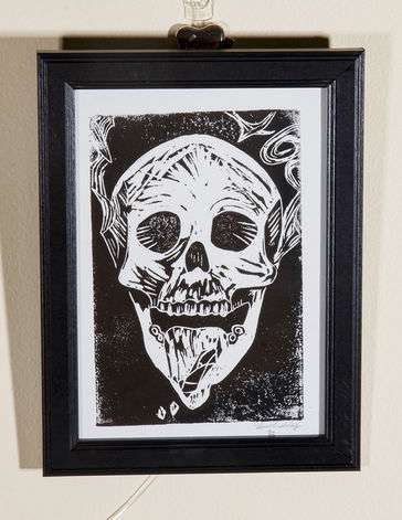 Black and white skull with tongue out, smoke swirling from ears and crystal on tongue.