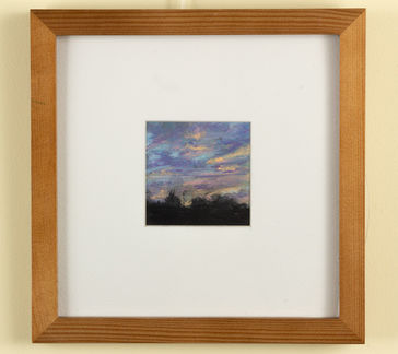 A purple, blue, and yellow sunset over a dark treeline. 