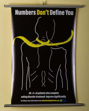 A skeletal looking person with a tape measure around their neck. 