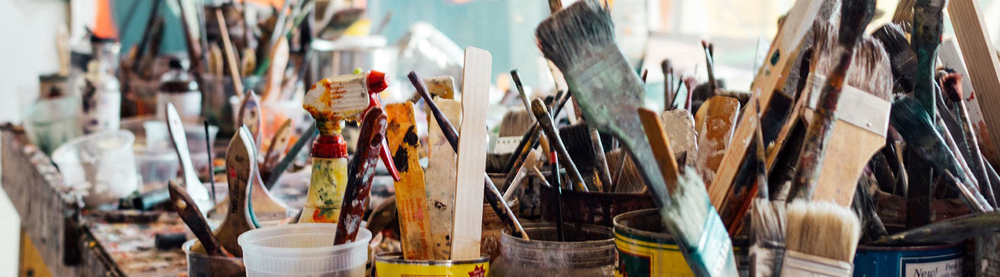 Table filled with Painbrushes and other Painting Supplies